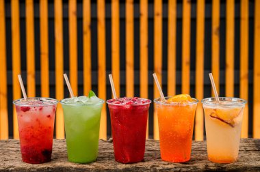 Plastik bardaklarda yaz limonataları şeffaf bardakta renkli limonatalar farklı meyve kokteylleriyle dolu limonatalar.