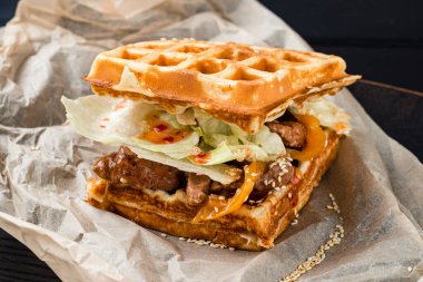 Et ve salatalı waffle sandviçi. Tahta masa arkasında etli ve sebzeli waffle sandviçi. Keto kahvaltısı. Belçika Waffle Sandviçi Viyana Waffle 'ı