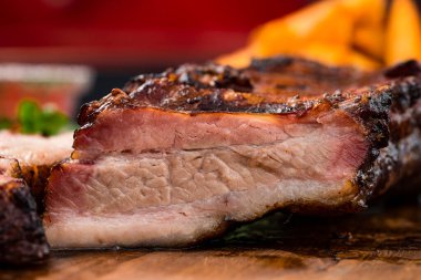 Mangalda ızgara kaburga ve ahşap bir masada ızgara ızgara Makro yakın çekim, eski ahşap bir masa üzerinde kızarmış patates ve sos ile barbekü kaburga yakın