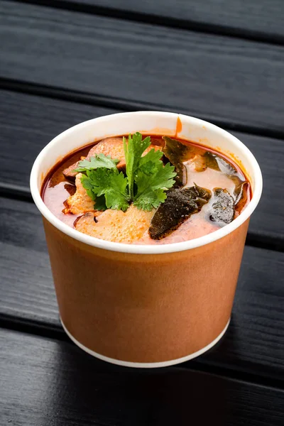 tom yam soup in a paper bowl to take away, traditional Thai tom yam soup. Delivery concept. Eco packages concept