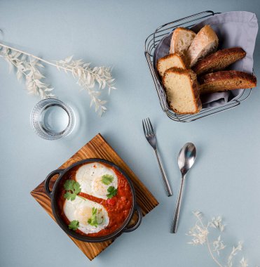 Dökme demir bir tavada yumurta, domates ve maydanozlu Shakshuka, geleneksel İsrail karıştırılmış Arapça domatesli yumurta.