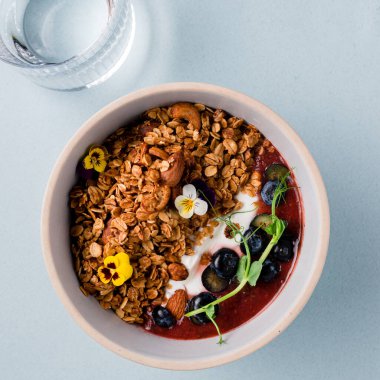 Yoğurtlu granola, badem ve taze yaban mersini. Müsli sağlıklı kahvaltı yulaf lapası taze yaban mersini, badem ve yoğurt tabakta, düz yerde yatıyordu.