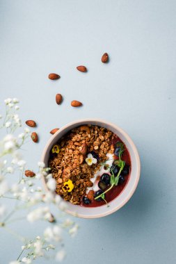 Yoğurtlu granola, badem ve taze yaban mersini. Müsli sağlıklı kahvaltı yulaf lapası taze yaban mersini, badem ve yoğurt tabakta, düz yerde yatıyordu.