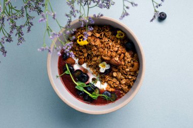 Yoğurtlu granola, badem ve taze yaban mersini. Müsli sağlıklı kahvaltı yulaf lapası taze yaban mersini, badem ve yoğurt tabakta, düz yerde yatıyordu.
