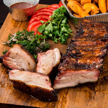 Tahtada ızgara pirzola, eski ahşap bir masada ızgara pirzola, patates kızartması ve sos.