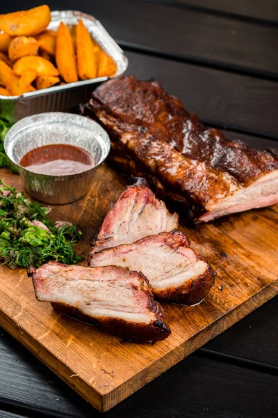 Tahtada ızgara pirzola, eski ahşap bir masada ızgara pirzola, patates kızartması ve sos.