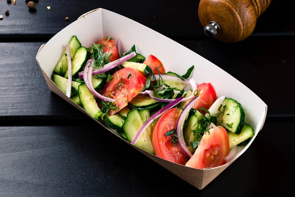 fresh vegetable salad in a takeaway box on a black background, Fresh organic mixed green salad in carton kraft box