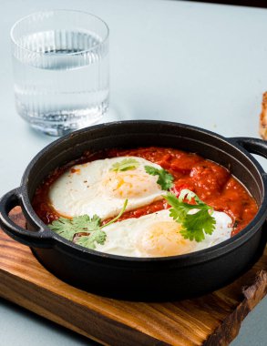 Dökme demir bir tavada yumurta, domates ve maydanozlu Shakshuka, Arapça domatesli geleneksel İsrail Shakshuka yumurta ve kopyalama alanı arka planı.