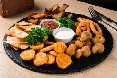Bira atıştırmalıkları, kombo atıştırmalıkları bira aperatifleri, kızarmış ekmekler. Deef Fried Chicken Nuggets, Cheese Fingers, soğan halkaları ahşap masada tempura.