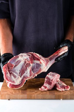 Şefin ellerinde çiğ kuzu jambon. Erkek kasap ellerinde çiğ et, kuzu bacağı eti tutuyor. paleo diyeti, kopyalama alanı olan organik yiyecekler.