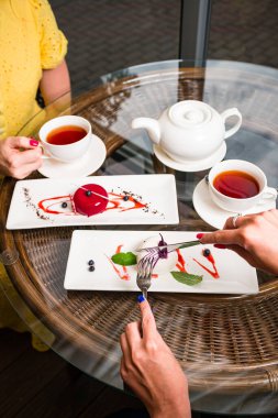 İki bayan arkadaş kremalı pasta yiyor Fransız tatlısını yiyor ve bir kafede çay içiyor, kremalı tatlı yiyor bir arkadaşla kafede kahvaltı yapıyor.