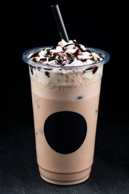Kremalı ve soslu buzlu kahve siyah arka planda izole edilmiş.