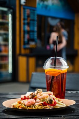 Deniz ürünleri karidesi ve midyeli pilav, deniz ürünleri karidesli lezzetli pirinç, mürekkep balığı, midye ve sebze, sokak kafesinde siyah bir arka planda.