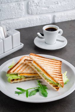 Peynirli tost, yumurtalı yumurta ve masada kahve ile salata kahvaltısı. Beyaz tabakta tost ekmeğinden yapılmış ev yapımı yumurtalı sandviç.