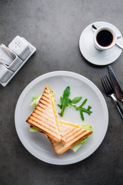 Peynirli tost, yumurtalı yumurta ve masada kahve ile salata kahvaltısı. Beyaz tepsi manzaralı, tost ekmeğinden yapılmış ev yapımı yumurtalı sandviç.