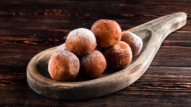 Taze kızarmış çörekler, pudra şekerli ahşap arka plan, kırsal stil küçük yuvarlak çörekler, koyu ahşap bir masa üzerinde.