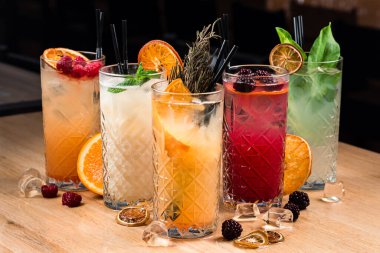 Bar tezgahında beş renkli cin tonik kokteyli, tezgahta beş limonata.