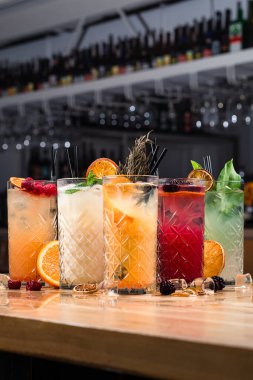 Bar tezgahında beş renkli cin tonik kokteyli, tezgahta beş limonata.