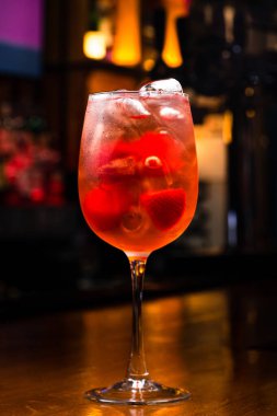Çilekli soğuk kokteyl aperolü, koyu arkaplanda şeffaf yüksek camlı çilekli aperol kokteyli. Aperol İtalyan meyve bazlı aperatif.