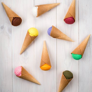 Beyaz masa manzaralı renkli dondurma külahı, külahlı farklı aromalı dondurmalar. Bir sürü dondurma kepçesi. Farklı tatlarda renkli dondurma kepçeleri.