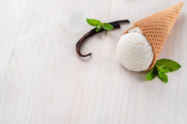 Vanilyalı ve naneli beyaz dondurma, beyaz arka planda bir külahta dondurma, ahşap zemin üzerinde vanilyalı dondurmalı waffle külahının yaz kompozisyonu.