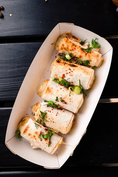 lavash with grilled cheese, Grilled rolls of bread lavash with cheese suluguni, peppers, picnic lunch, snack, delicious dish in takeaway box top view, flat lay