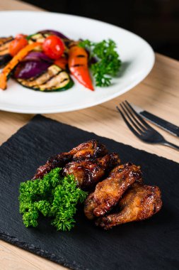 Kafe masasında servis edilen kızarmış ızgara tavuk kanatları ahşap masada duran tavuk kanadı tablası. Bufalo stili tavuk kanadı.