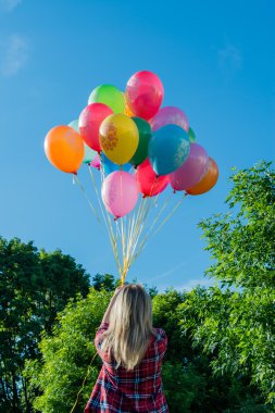 genç kadın, açık havada elinde renkli lateks balonlar