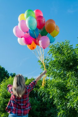 genç kadın, açık havada elinde renkli lateks balonlar