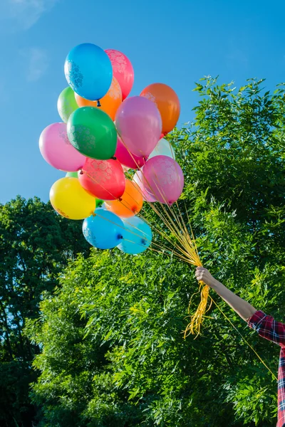Красочные латексные воздушные шары в руке молодой женщины, на открытом воздухе — стоковое фото