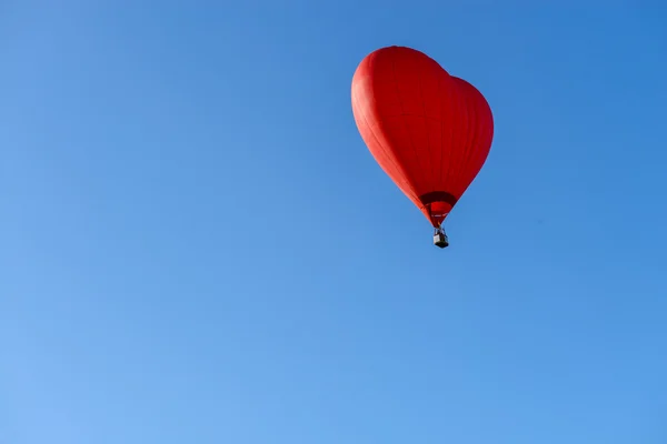 Globo de aire caliente rojo en forma de corazón contra el cielo azul — Foto de Stock