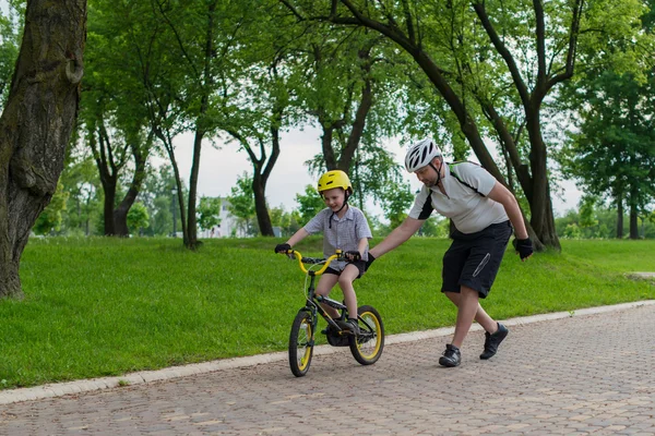 Vater und Sohn lernen Radfahren im Park und haben Spaß daran, — Stockfoto