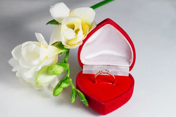 Goldener Verlobungsring in einer herzförmigen Schachtel und einem Blumen-Freesi — Stockfoto