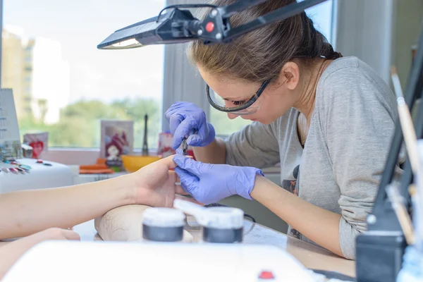 Primo piano della manicure al lavoro nel salone chiodo (DOF superficiale; co — Foto Stock