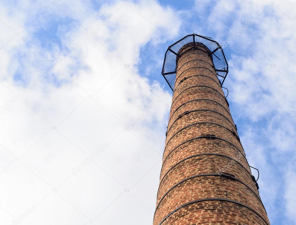 brick chimney of the plant view from below against the blue sky