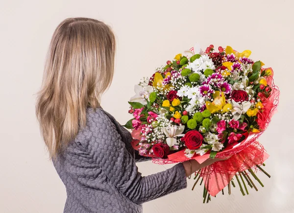 Mädchen mit braunen Haaren mit einem schönen Strauß in der Hand zurück zu th — Stockfoto