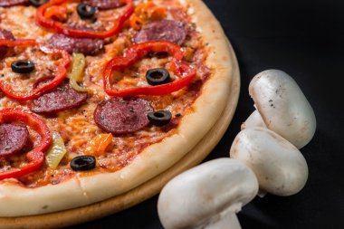 closeup lezzetli pizza domates, mantar, sosis, fesleğen ve siyah bir arka plan (sığ Dof chili biber ile)