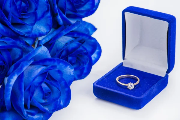 Golden engagement ring in a blue velvet box and blue rose (shallow DOF) — Stock Photo, Image