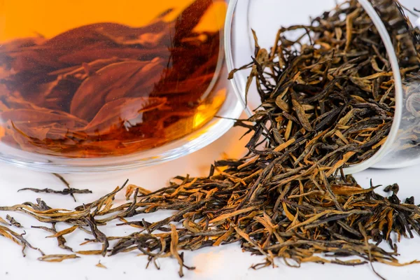 Nahaufnahme von verschüttetem Tee goldene Nadel mit einem rothaarigen (goldenen Affen) und aufgebrühtem Tee in einer Teekanne — Stockfoto