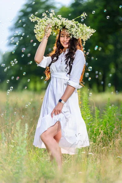 Slavische jonge vrouw met kroon op zijn hoofd houdingen in de achtergrond van de natuur — Stockfoto