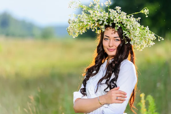 Slavische jonge vrouw met kroon op zijn hoofd houdingen in de achtergrond van de natuur — Stockfoto