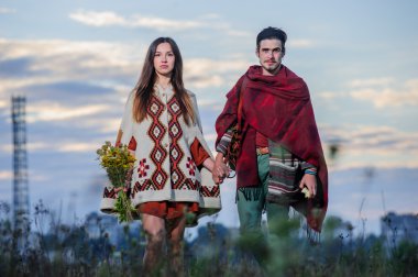 Sabah gökyüzü arka plan şekilde giyinmiş hippi çift poz