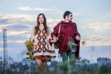 Sabah gökyüzü arka plan şekilde giyinmiş hippi çift poz