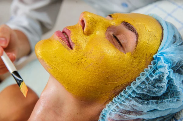 Belle femme avec masque facial doré . — Photo
