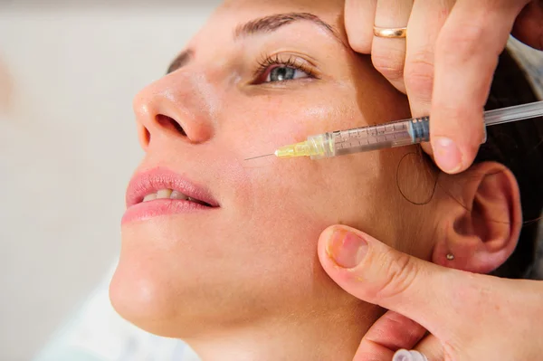 Schöne Frau mit goldener Gesichtsmaske im Schönheitssalon. — Stockfoto