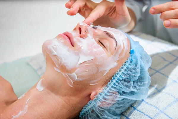 Mooie vrouw met gouden gezichtsmasker op beauty salon. — Stockfoto