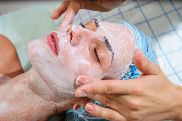 Mujer joven y relajada recibiendo un masaje facial con crema . — Foto de Stock