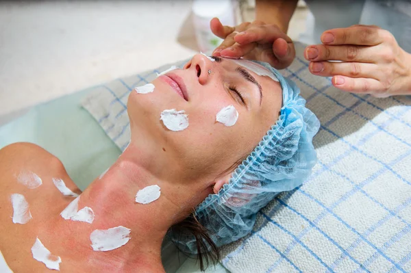 Belle femme avec masque facial doré au salon de beauté . — Photo