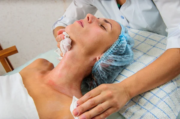 Mujer joven y relajada recibiendo un masaje facial con crema . — Foto de Stock