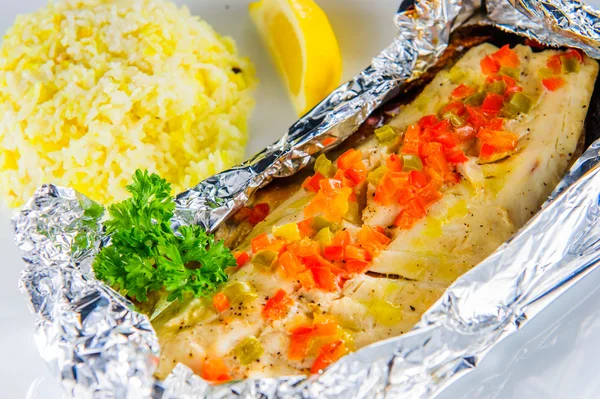 Teller mit gebackenem Fisch mit Gemüse in Folie. Nahaufnahme. — Stockfoto